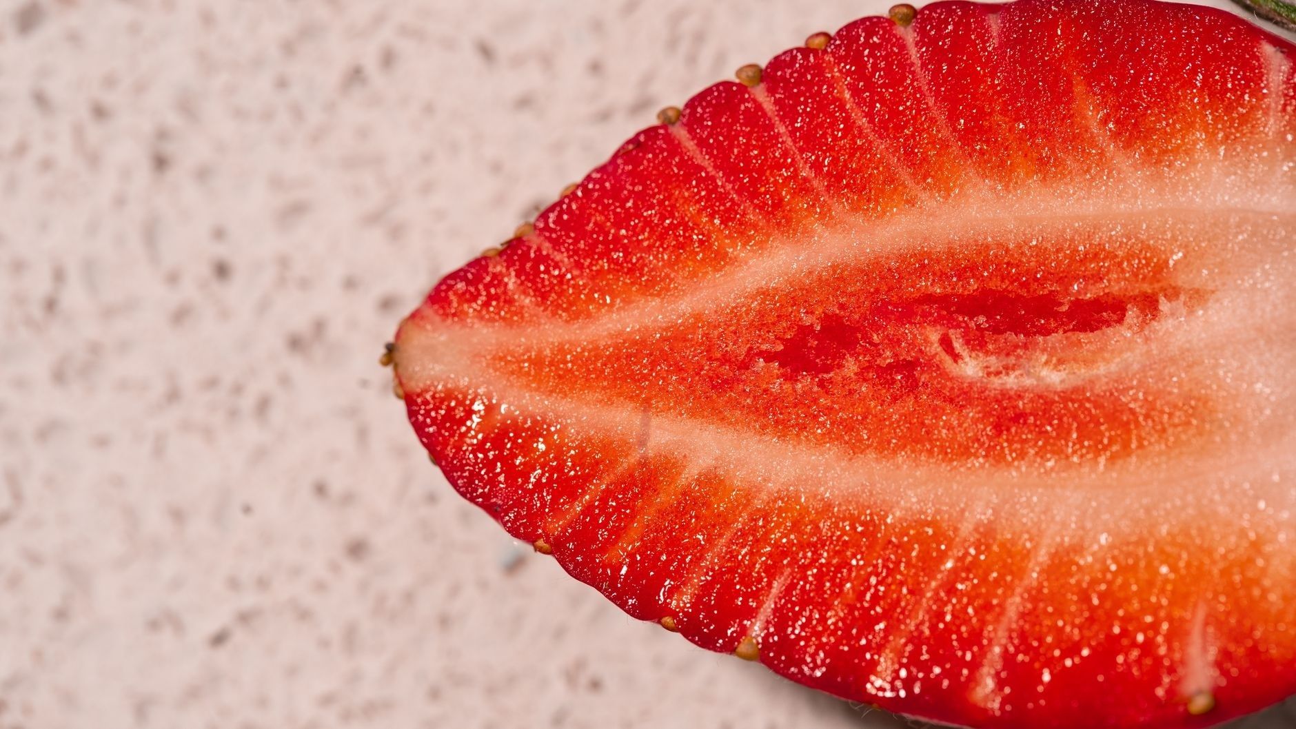 Close-up cross-section of a red strawberry with visible seeds and pale interior