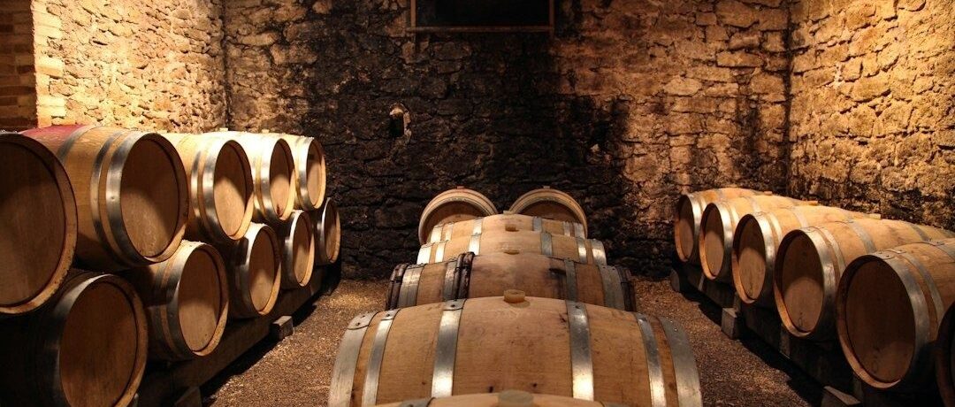 Oak barrels arranged in a warmly lit stone aging cellar