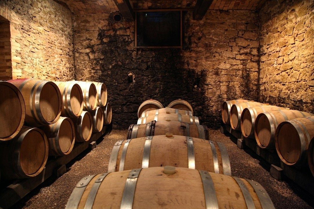 Oak barrels arranged in a warmly lit stone aging cellar