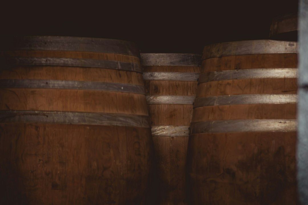 Large wooden barrels with darkened staves in a dim cooperage