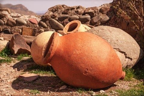 Large terracotta amphora lying among stones in a rugged landscape